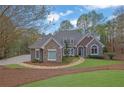 Charming home with stone accents, arched windows, mature trees, and well-maintained landscaping at 8385 Sentinae Chase Dr, Roswell, GA 30076