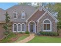 Attractive home featuring stone accents, arched windows, dormers, and lush landscaping at 8385 Sentinae Chase Dr, Roswell, GA 30076