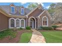 Elegant home featuring a stone facade, arched windows, dormers, and a beautifully landscaped yard at 8385 Sentinae Chase Dr, Roswell, GA 30076