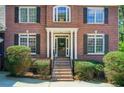 Inviting front entrance with brick steps and black shutters, complemented by lush greenery, creating a warm welcome at 201 Rippling Nw Dr, Marietta, GA 30064