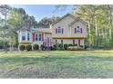Inviting two-story home with red shutters, manicured bushes, and a well-maintained lawn in a wooded setting at 6040 Carriage Dr, Cumming, GA 30028