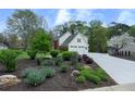 Beautifully landscaped yard with lush greenery leading to a two-story home with a two-car garage at 4950 Willow Creek Dr, Woodstock, GA 30188