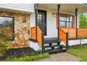 Welcoming front porch with decorative wooden railing, black front door, stone accents, and fresh landscaping at 10386 Wisteria Ln, Jonesboro, GA 30238
