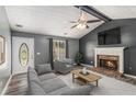 Comfortable living room with gray walls, fireplace, ceiling fan, vaulted ceiling, and neutral furnishings at 173 Michael Ln, Mcdonough, GA 30252