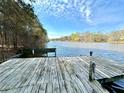 Picturesque view from a wooden dock overlooking a serene lake, with lush trees and a clear blue sky at 123 Wildwood Dr, Temple, GA 30179
