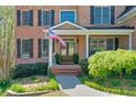 Inviting front entrance with brick steps, an American flag, and lush landscaping leading to a covered porch at 205 Northampton Ct, Canton, GA 30115