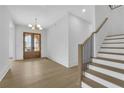 Bright foyer boasts hardwood floors, stairs with black spindles, and view of front door at 380 Hillcrest View Dr, Suwanee, GA 30024