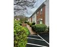 View of brick townhouses surrounded by lush green bushes and a pathway at 104 Holcomb Ferry Rd, Roswell, GA 30076