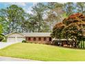 Charming single story brick home with a well-manicured lawn, mature trees, and attached two-car garage at 1152 Old Coach Rd, Stone Mountain, GA 30083