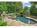 A backyard oasis featuring a stone-accented pool, spa, and outdoor fireplace with a waterfall feature at 2726 Mabry Ne Rd, Atlanta, GA 30319