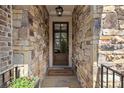 Stone entrance featuring a welcoming doormat, potted flowers, and glass paneled door at 705 Abbington River Ln, Atlanta, GA 30339