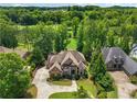 An aerial view of an estate home with mature trees, a sprawling lawn, and a large circular driveway at 6935 Wakehurst Pl, Cumming, GA 30040