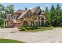 Side view of a luxurious brick and stone house with a three-car garage and meticulously landscaped yard at 6935 Wakehurst Pl, Cumming, GA 30040