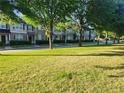 Street view of townhomes with manicured lawns and mature trees providing shade at 5449 Festival Ave, Fairburn, GA 30213