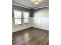 Bright room with hardwood flooring, gray accent walls, white trim, and large windows offering ample natural light at 5990 Arbor Green Cir, Sugar Hill, GA 30518