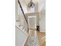 Bright foyer with hardwood floors, a staircase, and a view of the front door and chandelier at 125 Ketton Xing, Johns Creek, GA 30097