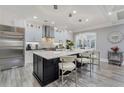 Modern white kitchen featuring stainless steel appliances, a large island with seating, and hardwood floors at 2444 Ballantrae Cir, Cumming, GA 30041