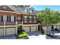Charming townhome with a two-car garage, red brick facade, and manicured landscaping enhances curb appeal at 7512 Portbury Park Ln, Suwanee, GA 30024