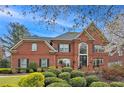 Charming brick home with a manicured lawn, lush landscaping, and classic architectural details at 9250 Nesbit Lakes Dr, Alpharetta, GA 30022