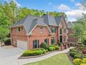 Spacious brick home with an attached garage, well-maintained lawn, and mature trees at 9250 Nesbit Lakes Dr, Alpharetta, GA 30022