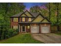 Charming two-story home with a brick facade, two-car garage, and well-manicured lawn and mature trees at dusk at 71 Anita Se Pl, Mableton, GA 30126