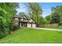 Charming two-story brick home with a two-car garage situated on a lush, green lawn surrounded by mature trees at 71 Anita Se Pl, Mableton, GA 30126