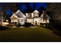 Stately home featuring a stone chimney, manicured lawn, mature landscaping, and charming exterior lighting at 1226 Goodwin Ne Rd, Atlanta, GA 30324