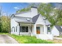 Elegant white farmhouse with a black metal roof, skylights, and a welcoming front porch at 3353 Hemphill St, Atlanta, GA 30337