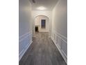 Elegant hallway with gray floors, arched doorway, detailed molding, and an open view to the living room at 1916 Oakwood Grove Dr, Snellville, GA 30078