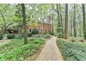 Two-story brick home with a brick walkway and a backdrop of mature trees, creating a serene atmosphere at 5884 Hammersmith Rd, Stone Mountain, GA 30087
