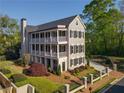 Three-story home boasts multiple balconies, gray siding, black shutters, and landscaped surroundings at 3890 The Battery, Duluth, GA 30096