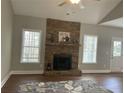 Cozy living room featuring a stone fireplace, hardwood floors, and natural light from two large windows at 106 Creek Crossing Ln, Temple, GA 30179