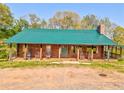 Charming log cabin with a metal roof, rocking chairs, and a covered porch at 1288 Reavesville Rd, Bowdon, GA 30108