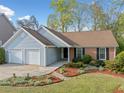 Inviting single-level home featuring a well-maintained lawn, brick facade, and two-car garage, surrounded by mature trees at 5265 Bentley Hall Dr, Alpharetta, GA 30005