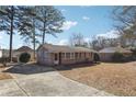 Brick home with a concrete driveway and mature trees on a sunny day at 8554 Taylor Rd, Riverdale, GA 30274