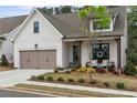 Inviting home with a two-car garage, covered porch, and blooming flowers in the front yard at 228 Idylwilde Way, Canton, GA 30115