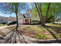 Attractive home with a two-car garage surrounded by lush greenery and mature trees on a sunny day at 4070 Amber Leaf Dr, Roswell, GA 30076