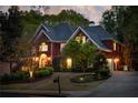 Exterior view of brick home at night featuring exterior lighting and mature trees at 225 Cotton Field Ct, Alpharetta, GA 30022