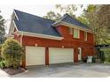 Spacious two-car garage attached to a classic red brick home with an adjacent pergola at 225 Cotton Field Ct, Alpharetta, GA 30022