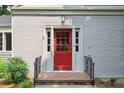Welcoming red front door with brick steps and black railings, framed by white trim and lush greenery at 404 Princeton Ne Way, Atlanta, GA 30307