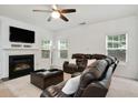 Comfortable living room with a fireplace, large windows, and plush leather seating under a modern ceiling fan at 1519 Dolcetto Nw Trce # 1, Kennesaw, GA 30152