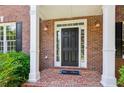 Inviting brick front porch with a black front door framed by white columns and side lights, plus a cute welcome mat at 7020 Weybridge Dr, Cumming, GA 30040