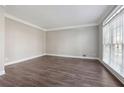 Bright and airy living room with hardwood floors, neutral paint, crown molding, and natural light from a large window at 760 Woodrow Dr, Lawrenceville, GA 30043