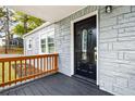 Inviting front porch featuring a decorative door, stone-look exterior, a wooden railing, and well-maintained landscaping at 1623 Athens Sw Ave, Atlanta, GA 30310