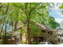 View of a two-story townhouse with a wooden deck entrance framed by mature trees at 2109 Defoors Ferry Nw Rd # D, Atlanta, GA 30318