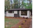 A home exterior, painted white brick, featuring stylish landscaping and contrasting black trim and dark wood privacy screen at 3572 Adkins Nw Rd, Atlanta, GA 30331