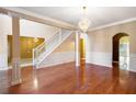 Spacious living room featuring hardwood floors, decorative pillars, and a chandelier, with adjacent rooms at 4312 Defoors Farm Trl, Powder Springs, GA 30127