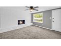 Cozy living room features a fireplace, a ceiling fan, a window, and gray carpet at 4301 Hidden Valley Rd, Decatur, GA 30035