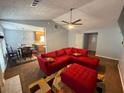 Open-concept living room with red sectional seating, fireplace, ceiling fan, and connecting dining area at 221 Huntington Dr, Mcdonough, GA 30253