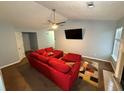 Cozy living room with a ceiling fan, a large television, and comfortable red sectional sofa at 221 Huntington Dr, Mcdonough, GA 30253